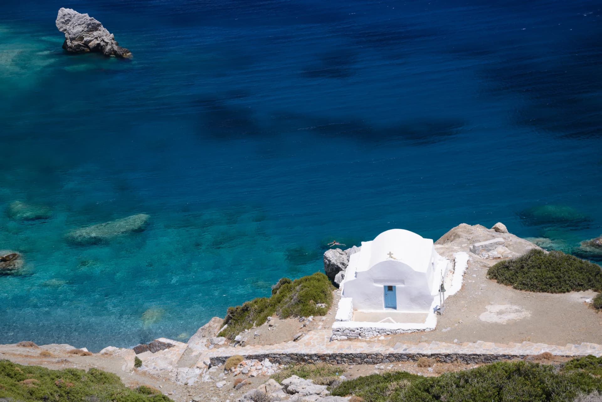 The small church of Agia Anna perched above the deep blue bay, famously featured in "The Big Blue"